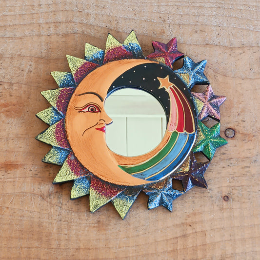 Bring celestial charm and positive energy into your home with this little Handmade Moon &amp; Stars Mirror. Carefully crafted by Fair Trade artisans, this unique decorative mirror features a stunning purple crescent moon design that adds a mystical and spiritual touch to any room.
