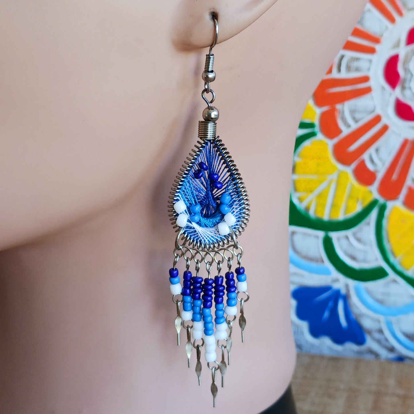 Add a splash of colour to your look with these beautiful handmade Peruvian woven teardrop earrings. Inspired by the vibrant colours and patterns of a peacock feather, each earring features intricate woven detailing complemented by coordinating beads and delicate silver-tone embellishments.