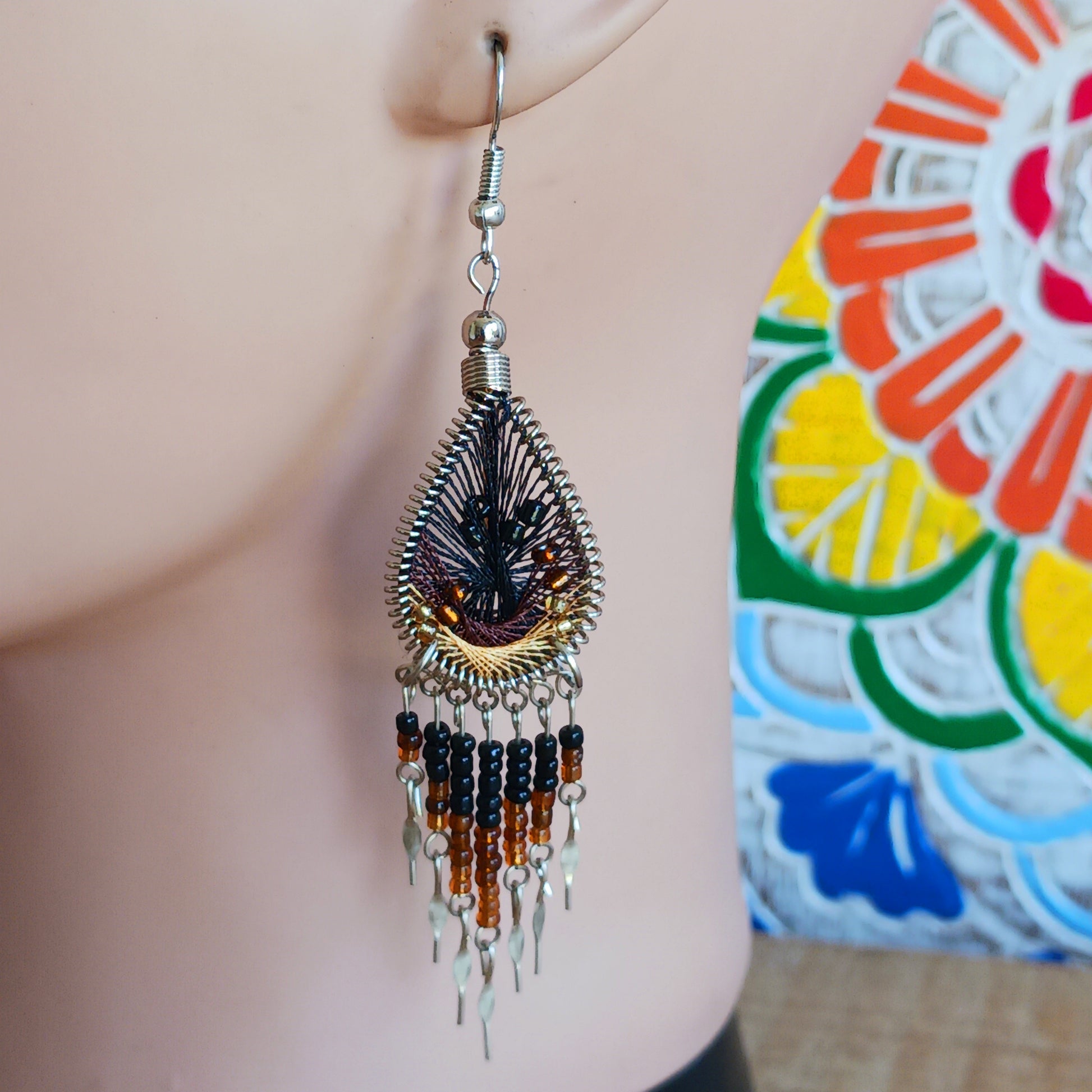 Add a splash of colour to your look with these beautiful handmade Peruvian woven teardrop earrings. Inspired by the vibrant colours and patterns of a peacock feather, each earring features intricate woven detailing complemented by coordinating beads and delicate silver-tone embellishments.