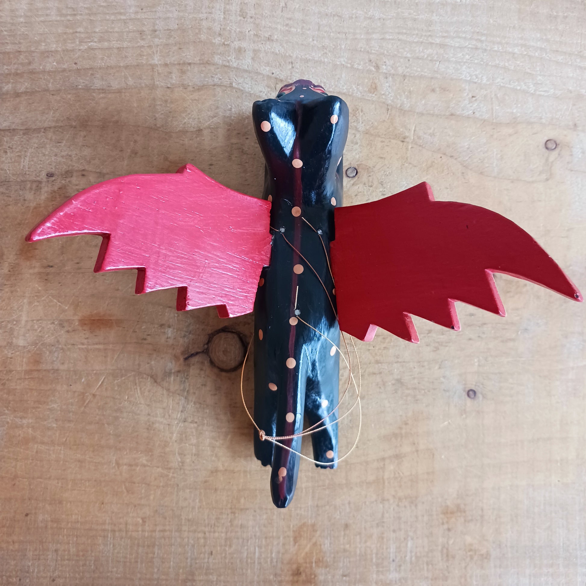 Bring a touch of mystery and magical drama to your home with this striking flying cat mobile, hand carved and painted by skilled artisans in Bali. Featuring a deep black cat with vivid red wings and intricate painted detailing, this unusual hanging decoration makes a bold statement wherever it is displayed.