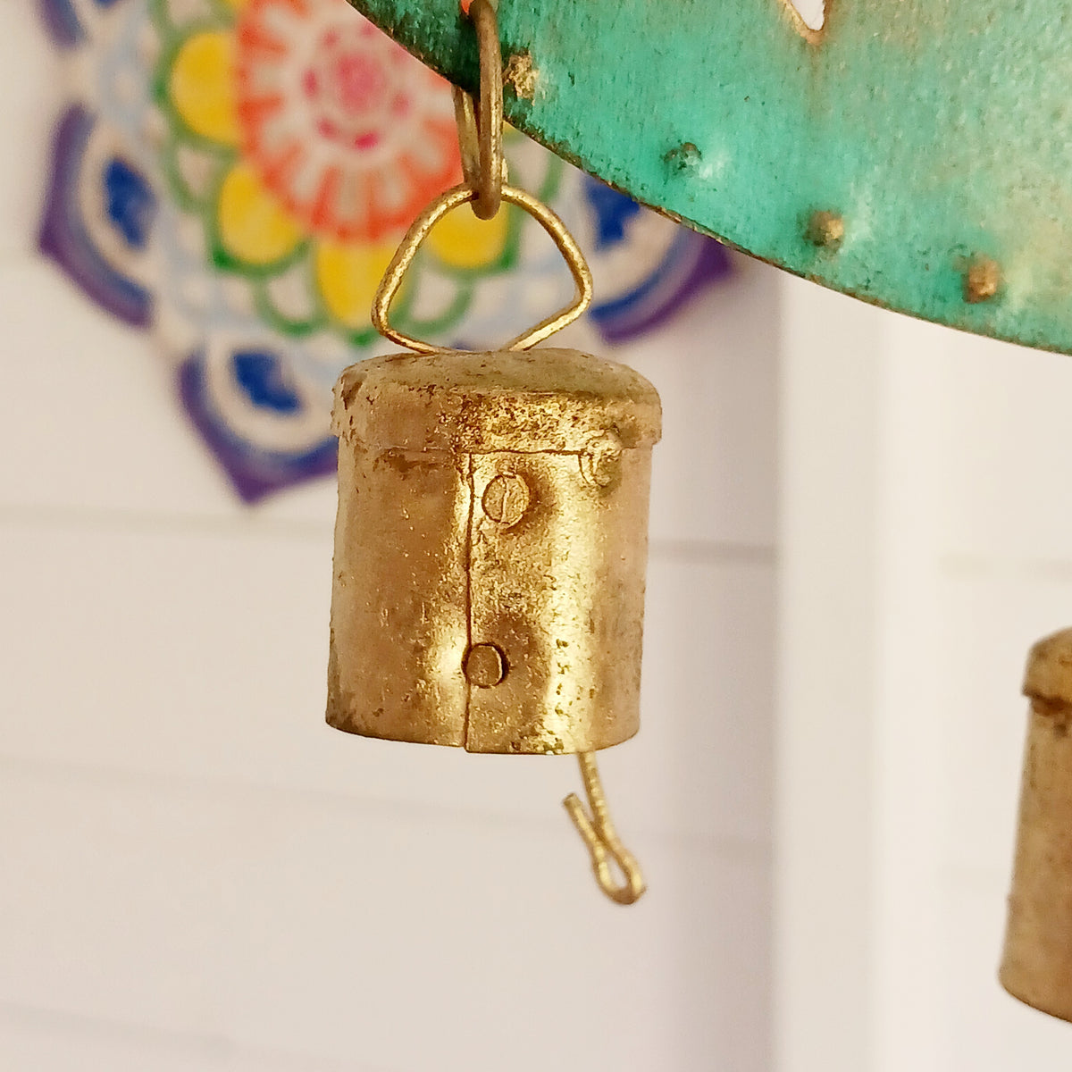 Bring a touch of celestial charm to your home with this rustic crescent moon wind chime, beautifully finished in an aged verdigris green. Handmade by skilled artisans in India, this decorative iron wall hanging features pierced star detailing, a hanging star charm and traditional Indian brass bells.