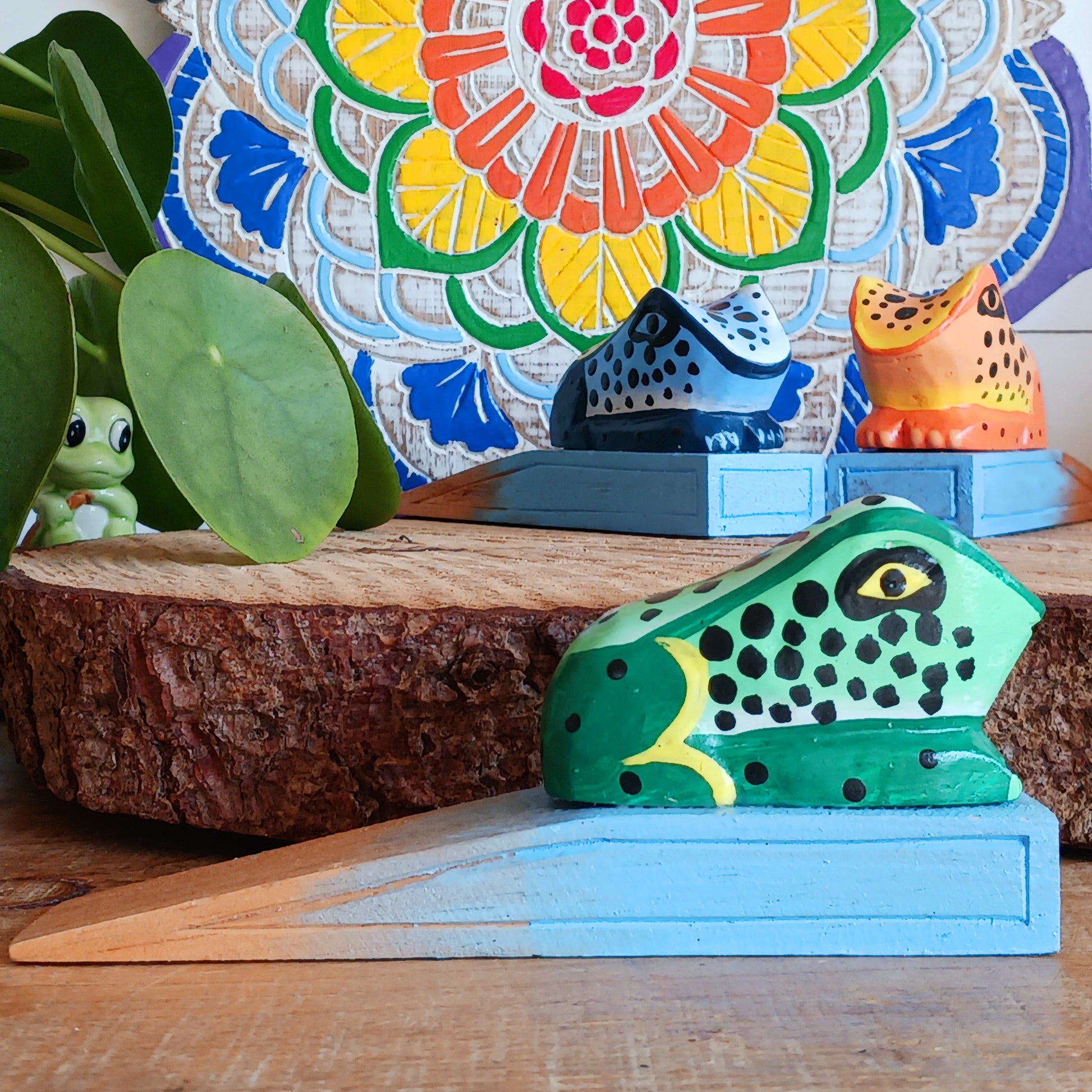 Bring charm and character into your home with this decorative wooden door stopper, featuring a turquoise base and a playful, hand-painted dotty frog design in vibrant blue, green, and orange. Perfect for propping open doors in style, this quirky wedge door stop is both practical and fun.